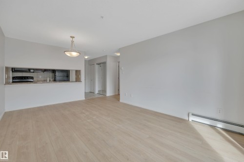 The property features an open living area with light-toned flooring and neutral walls - 108 1204 156 Street, Edmonton, AB - Indoor Photo Showing Kitchen
