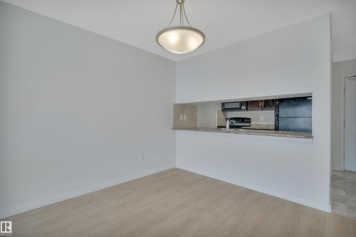 This open-concept area features light-colored flooring and a contemporary overhead light fixture - 108 1204 156 Street, Edmonton, AB - Indoor Photo Showing Kitchen