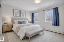 This bedroom features two windows, light-colored walls, and a ceiling-mounted light fixture *AI generated photo* - 108 1204 156 Street, Edmonton, AB  - Indoor Photo Showing Bedroom 