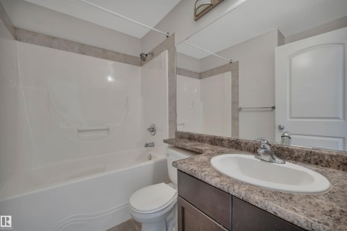 The bathroom features a combined shower and tub with a white finish, a vanity with a countertop and an integrated sink, and a mirror - 108 1204 156 Street, Edmonton, AB - Indoor Photo Showing Bathroom