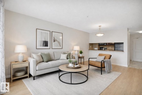Living area featuring light-toned flooring, light-colored walls, and an open pass-through to a kitchen area with a counter *AI generated photo - 108 1204 156 Street, Edmonton, AB - Indoor Photo Showing Living Room