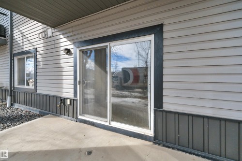 The property features a concrete patio area, a sliding glass door, and vinyl siding with a contrasting trim - 108 1204 156 Street, Edmonton, AB - Outdoor With Exterior