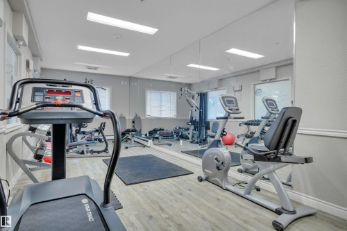 This fitness room features light-toned flooring, full-length wall mirrors, and recessed lighting - 108 1204 156 Street, Edmonton, AB - Indoor Photo Showing Gym Room