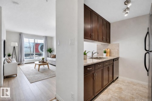 The property features a kitchen with dark wood cabinetry, a double basin sink, and stainless steel appliances *AI generated photo - 108 1204 156 Street, Edmonton, AB - Indoor