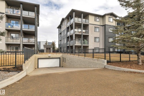 The property features a concrete entrance ramp leading to a white garage door, with black metal fencing visible at ground level - 108 1204 156 Street, Edmonton, AB - Outdoor With Balcony