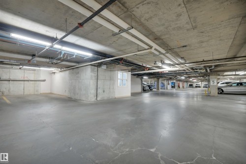 Subterranean parking garage featuring a concrete floor and ceiling, exposed piping, and fluorescent lighting - 108 1204 156 Street, Edmonton, AB - Indoor Photo Showing Garage
