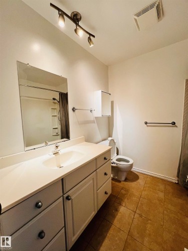 Bathroom featuring a vanity with a countertop sink, a wall-mounted mirror, and tiled flooring - 11459 51 Avenue, Edmonton, AB - Indoor Photo Showing Bathroom