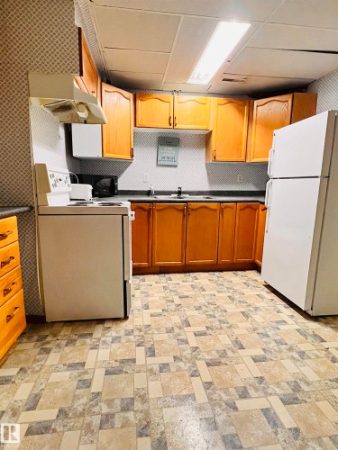 The property features a kitchen with light wood cabinetry, a white refrigerator, and a white range - 11459 51 Avenue, Edmonton, AB - Indoor