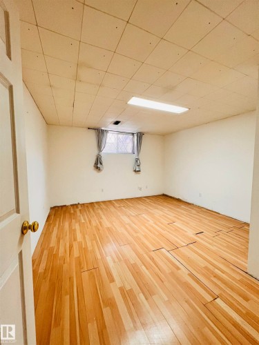 The room features light-toned wooden flooring, white walls, and a window with gray drapes - 11459 51 Avenue, Edmonton, AB - Indoor
