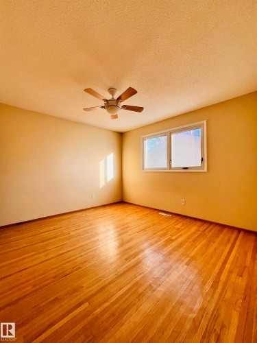 This room features rich hardwood flooring, a ceiling fan, and windows that allow natural light into the space - 11459 51 Avenue, Edmonton, AB - Indoor Photo Showing Other Room