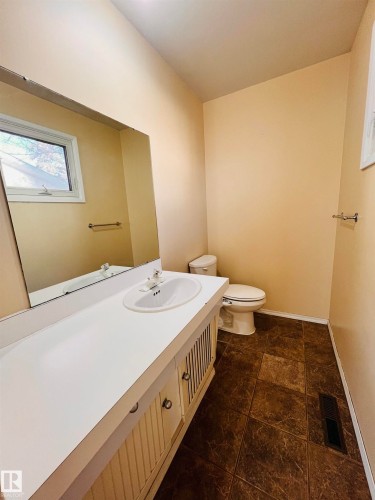 Bathroom featuring a vanity with a white countertop and an integrated sink, a large mirror, a window, and tiled flooring - 11459 51 Avenue, Edmonton, AB - Indoor Photo Showing Bathroom