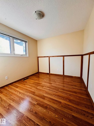 This room features wood-look flooring, light-colored walls, and a window providing natural light - 11459 51 Avenue, Edmonton, AB - Indoor Photo Showing Other Room