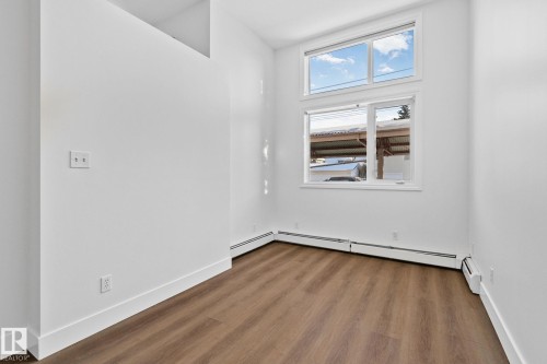 This room features white walls, hardwood flooring, and a large window providing natural light - 116 11033 127 Street, Edmonton, AB - Indoor Photo Showing Other Room