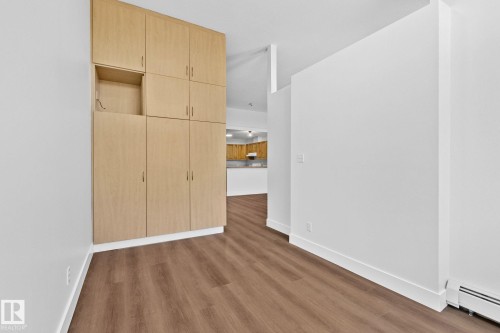 This space features built-in cabinetry, durable flooring, and white walls - 116 11033 127 Street, Edmonton, AB - Indoor Photo Showing Other Room