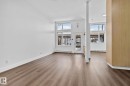 This expansive room features wide plank flooring and white walls, creating a bright and airy atmosphere - 116 11033 127 Street, Edmonton, AB  - Indoor Photo Showing Other Room 