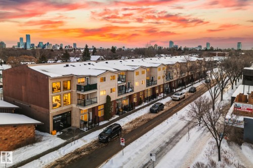 The property features multi-story townhomes with balconies, set along a snow-covered street - 116 11033 127 Street, Edmonton, AB - Outdoor With View