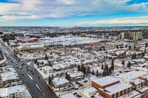 Aerial view of the surrounding area featuring roads with vehicles, various buildings, and snow-covered landscapes - 116 11033 127 Street, Edmonton, AB - Outdoor With View