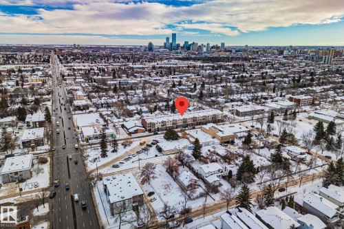 Aerial view showcasing the property's location within a residential area with a prominent roadway and a city skyline visible in the distance - 116 11033 127 Street, Edmonton, AB - Outdoor With View