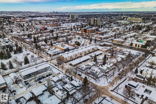 Aerial view of the surrounding neighbourhood featuring residential properties, trees, and roads, all covered in snow - 116 11033 127 Street, Edmonton, AB - Outdoor With View