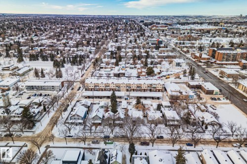 An aerial view showcasing a neighborhood with residential properties and commercial buildings, all covered in snow - 116 11033 127 Street, Edmonton, AB - Outdoor With View