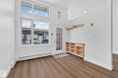 The entry area features modern wood-style flooring, a large window with additional transom windows, and a built-in storage unit with open shelving - 116 11033 127 Street, Edmonton, AB  - Indoor Photo Showing Other Room 