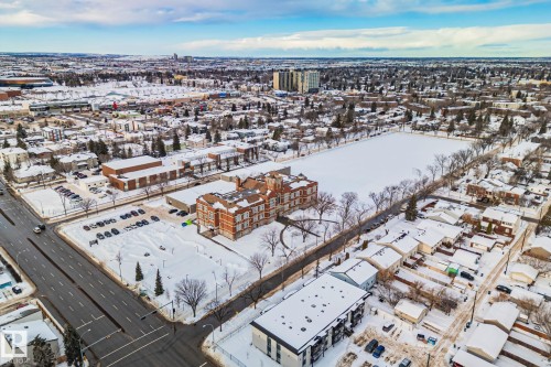 The property is set within a residential neighborhood featuring established trees, nearby park space, and a well-maintained street - 116 11033 127 Street, Edmonton, AB - Outdoor With View