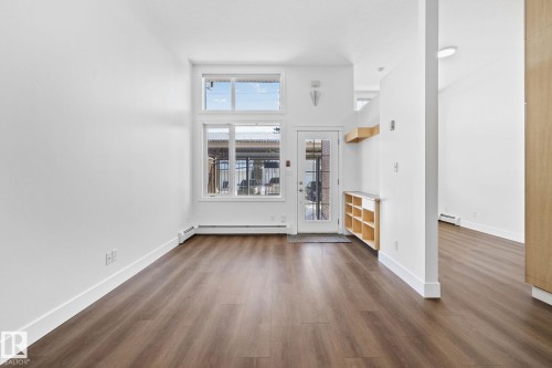 The living space features rich brown flooring and white walls, creating a bright and neutral palette - 116 11033 127 Street, Edmonton, AB - Indoor