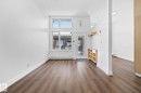 The living space features rich brown flooring and white walls, creating a bright and neutral palette - 116 11033 127 Street, Edmonton, AB  - Indoor 