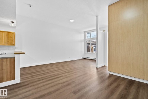 This inviting space features light wood cabinetry, a backsplash with rectangular tiles, and a window providing natural light - 116 11033 127 Street, Edmonton, AB - Indoor Photo Showing Kitchen