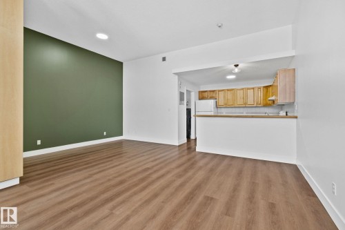 The spacious interior features hardwood style flooring, high ceilings with recessed lighting, and an accent wall - 116 11033 127 Street, Edmonton, AB - Indoor