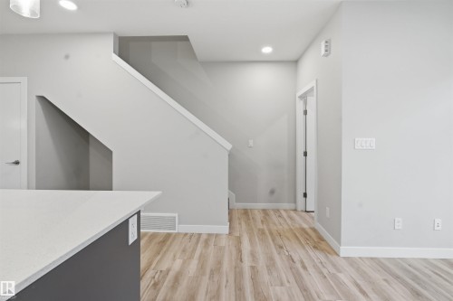 The property features light-colored flooring, neutral wall paint, and a staircase with white trim - 40 1729 Keene Crescent, Edmonton, AB - Indoor Photo Showing Other Room