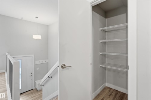 Entryway featuring a contemporary pendant light fixture, a door with a vertical window, and a coat rack with hooks - 40 1729 Keene Crescent, Edmonton, AB - Indoor