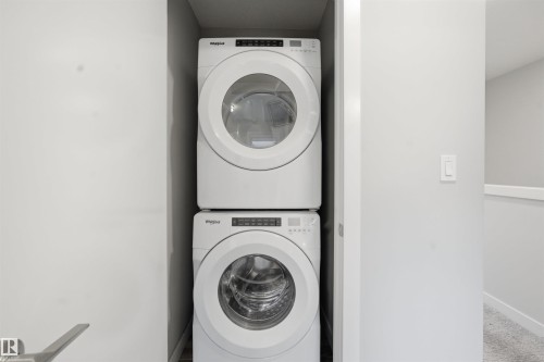 Convenient laundry space featuring a stacked washer and dryer unit - 40 1729 Keene Crescent, Edmonton, AB - Indoor Photo Showing Laundry Room