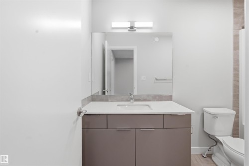 Bathroom featuring a modern vanity with a white countertop, an integrated sink, and a large mirror with overhead lighting - 40 1729 Keene Crescent, Edmonton, AB - Indoor Photo Showing Bathroom