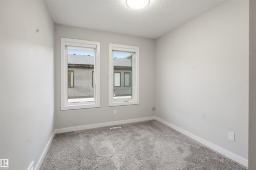 This room features neutral-toned walls, two windows, and a ceiling light fixture - 40 1729 Keene Crescent, Edmonton, AB - Indoor Photo Showing Other Room