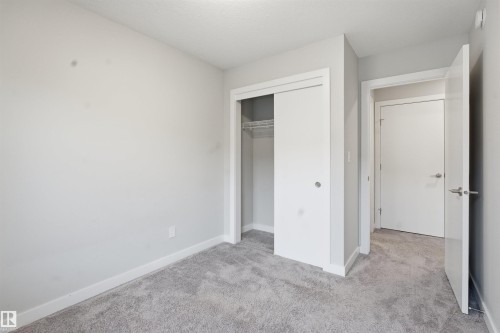This room features light grey carpeting, white baseboards, and a closet with sliding doors - 40 1729 Keene Crescent, Edmonton, AB - Indoor Photo Showing Other Room