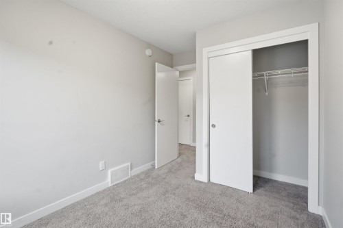This room features light grey walls, grey carpet flooring, and a closet with white sliding doors and wire shelving - 40 1729 Keene Crescent, Edmonton, AB - Indoor Photo Showing Other Room