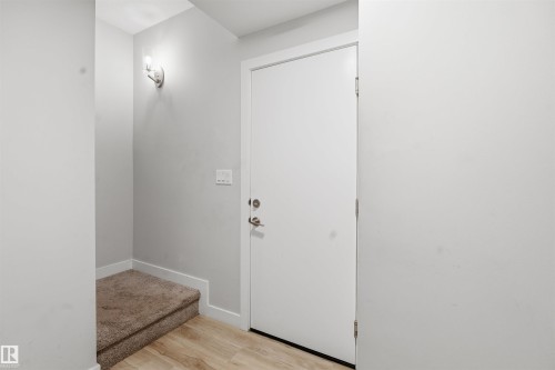 Entryway featuring light-colored walls, a white door with silver hardware, wood-style flooring, and a carpeted step - 40 1729 Keene Crescent, Edmonton, AB - Indoor Photo Showing Other Room