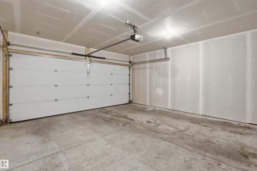 The property includes an attached garage with a concrete floor, a white sectional garage door, and interior lighting - 40 1729 Keene Crescent, Edmonton, AB - Indoor Photo Showing Garage