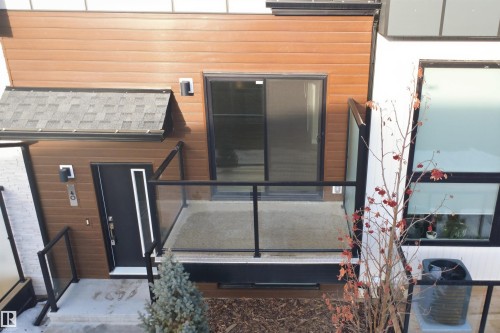 The property features a private balcony with glass railings, a sliding glass door, and a modern entry door with decorative glass inserts - 40 1729 Keene Crescent, Edmonton, AB - Outdoor With Exterior