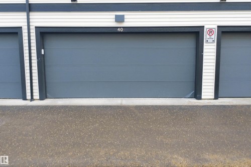The property includes a gray garage door with white siding and dark trim - 40 1729 Keene Crescent, Edmonton, AB - Outdoor