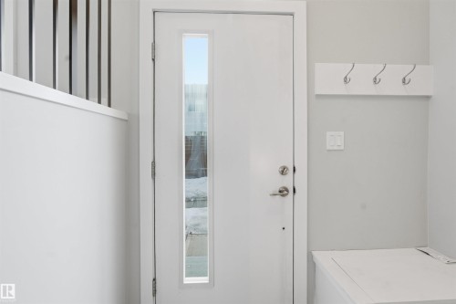 Entryway featuring a white door with a vertical window, light grey walls, and a white coat rack with four hooks - 40 1729 Keene Crescent, Edmonton, AB - Indoor Photo Showing Other Room