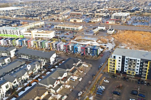 Aerial view showcasing the property's location within a developed community featuring residential buildings, commercial structures, and paved roads - 40 1729 Keene Crescent, Edmonton, AB - Outdoor With View