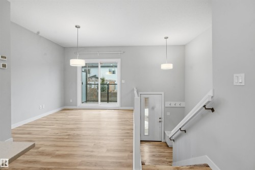 This open concept living space features light wood-style flooring and light gray walls - 40 1729 Keene Crescent, Edmonton, AB - Indoor Photo Showing Other Room