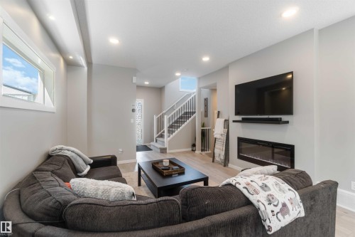 Living room with light-toned flooring, recessed lighting, and a modern wall-mounted fireplace - 29 Gambel Loop, Spruce Grove, AB - Indoor Photo Showing Living Room With Fireplace