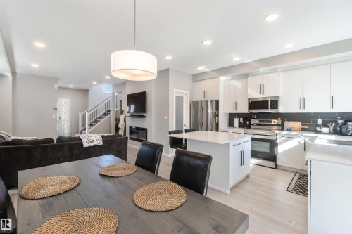 Open concept living area featuring a kitchen with white cabinetry, stainless steel appliances, and a central island - 29 Gambel Loop, Spruce Grove, AB - Indoor Photo Showing Kitchen With Upgraded Kitchen