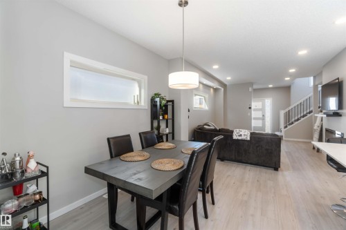 Dining area with a modern light fixture, featuring a rectangular table with seating for four, and light-colored flooring throughout - 29 Gambel Loop, Spruce Grove, AB - Indoor Photo Showing Dining Room
