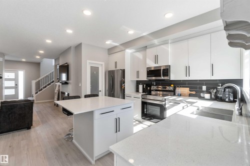 The kitchen features white cabinetry, stainless steel appliances, and a dark subway tile backsplash - 29 Gambel Loop, Spruce Grove, AB - Indoor Photo Showing Kitchen With Upgraded Kitchen