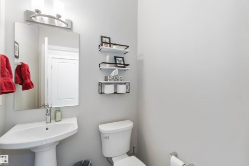 Bathroom featuring a pedestal sink, a wall-mounted mirror, and a toilet - 29 Gambel Loop, Spruce Grove, AB - Indoor Photo Showing Bathroom