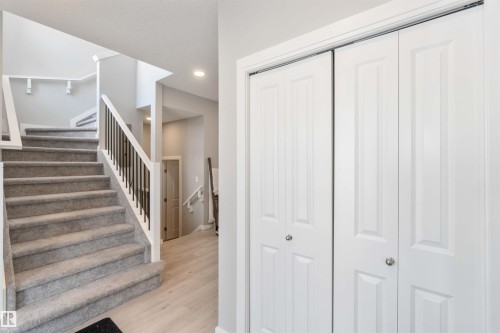 The property features a staircase with carpeted steps and a white and black railing, complemented by light-colored flooring - 29 Gambel Loop, Spruce Grove, AB - Indoor Photo Showing Other Room
